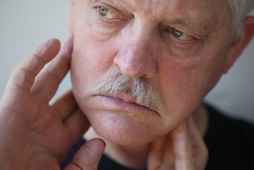 older man inspecting his neck in pain