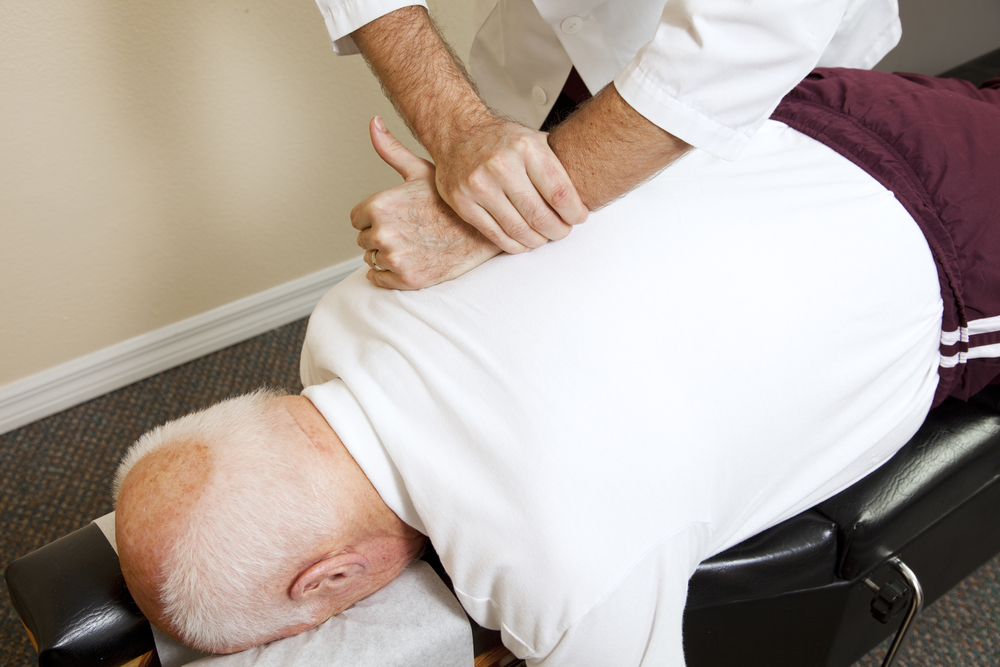 Chiropractor performing an adjustment on senior male