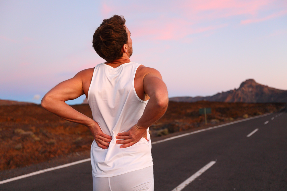 man in white tank top is running with back pain