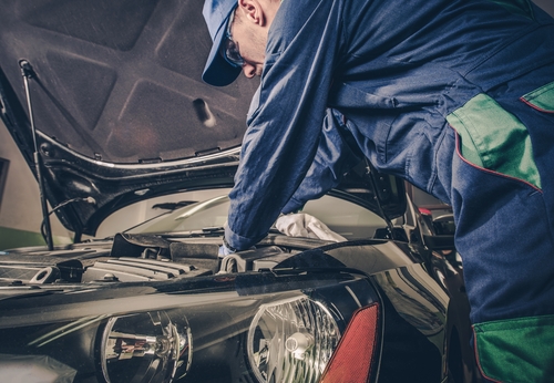 mechanic working on car with bent back