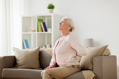 older woman with back pain sitting on couch