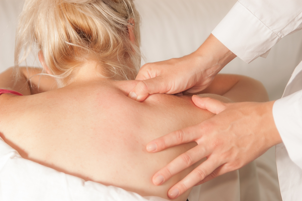 Close up of woman receiving trigger point therapy from a chiropractor