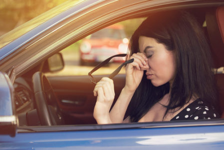 a woman in her car holding her nose in pain after a car accident